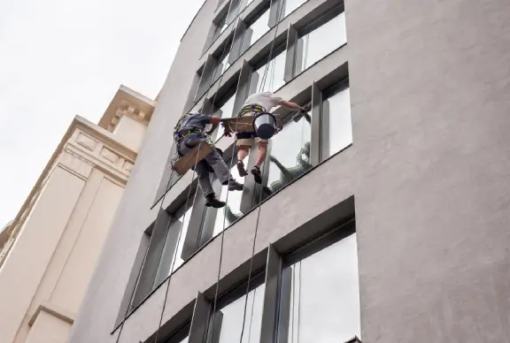 Two workers washing windows outside a building